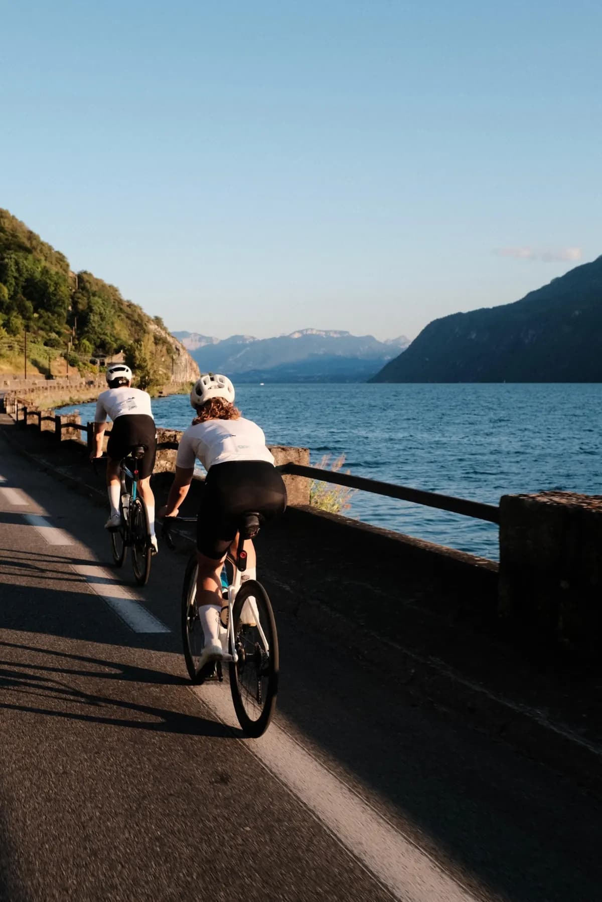 Deux cyclistes le long d'un lac de montagne, au soleil du soir.